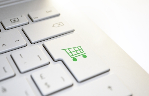 Photo of a computer keyboard with a green shopping cart on the enter key