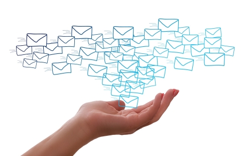 A photo of a hand holding up a bunch of illustrations of emails