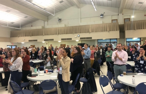 A photo of people standing and applauding in a large lecture hall