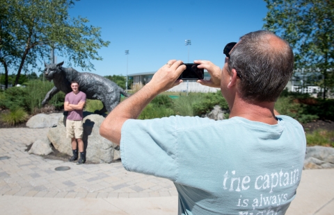 A photo of a father taking his son's photo on a mobile phone