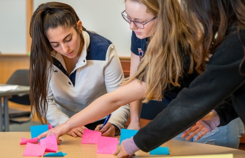 Three female college students review post-it notes