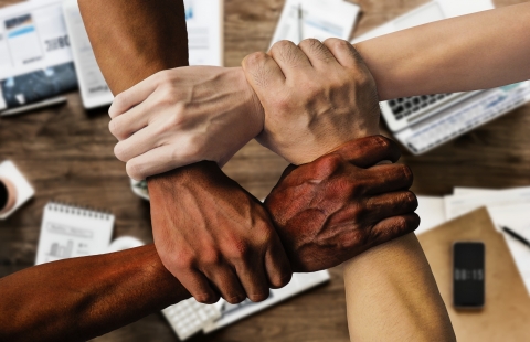 Photo of four hands grabbing opposite wrists