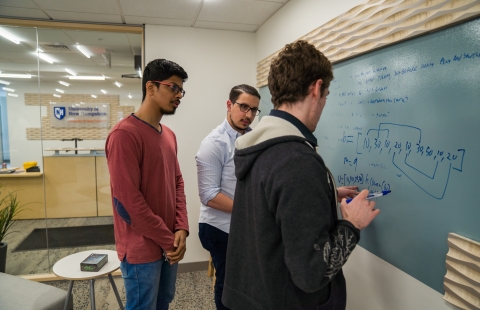 Three College Students Standing at a White Board