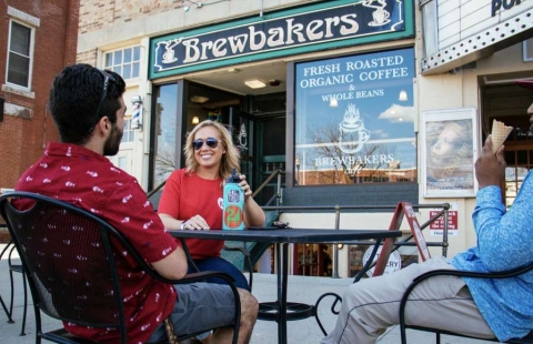 Photo of three college students sitting outside at a cafe