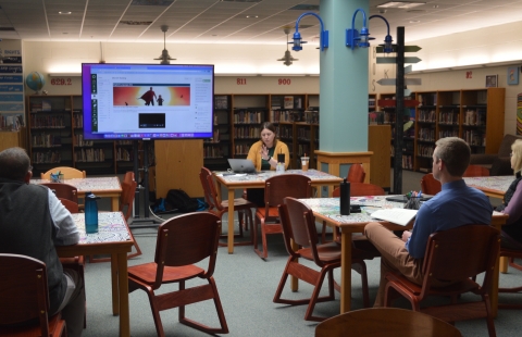 Teachers sitting in a library listening to a presentation