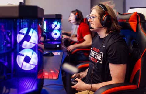 A college student sitting in a chair playing video games.