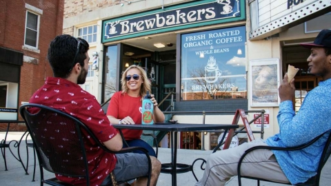 Photo of three college students sitting outside at a cafe