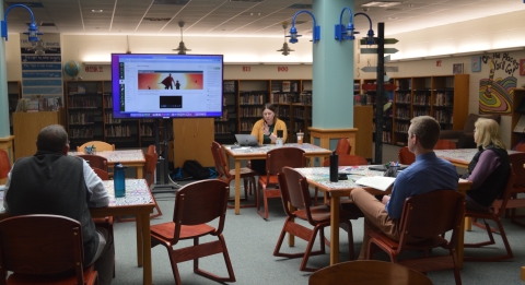 Teachers sitting in a library listening to a presentation