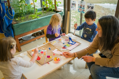 Adult plays with three children at a table