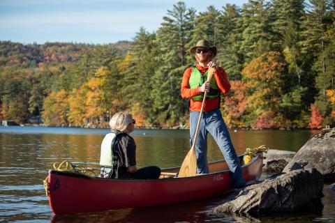 Two people in a canoe outside, one is standing